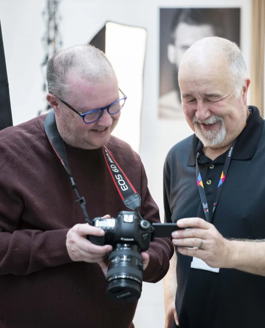 Two older students reviewing a photo on a DSLR camera screen in a professional studio setting. Two older students reviewing a photo on a DSLR camera screen in a professional studio setting.